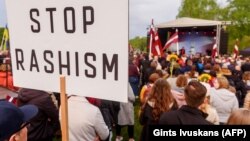"Остановить рашизм": плакат на акции в Риге с требованием снести советские монументы в Латвии, май 2022 года