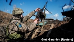 Український військовослужбовець тримає кулемет в окопі на позиції на передовій, ілюстраційне фото