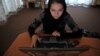 Компьютер пайдаланып отырған әйел. Ауғанстан, 22 маусым 2012 жыл. (Көрнекі сурет)