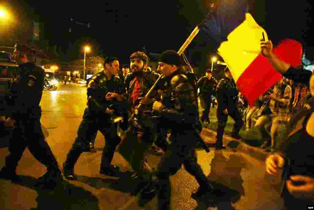 While the protests were mostly peaceful, riot police were occasionally called in. Here police in Bucharest detain a demonstrator. (EPA/Mihai Barbu)