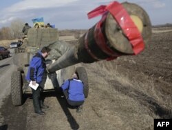 Observatori OSCE examinează un tun al armatei ucrainene.