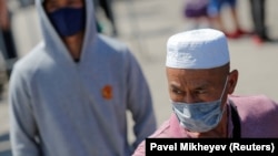 Жители в защитных масках у одного из блокпостов на въезде в Алматы, которые продолжили действовать после прекращения режима чрезвычайного положения в стране 11 мая.