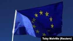 U.K. -- A protestor waves an EU flag as he walks past the Houses of Parliament in central London, Britain September 22, 2017