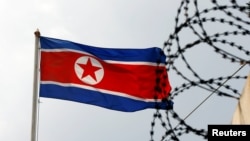 Флаг Северной Кореи на фоне колючей проволоки. Архивное фото.
