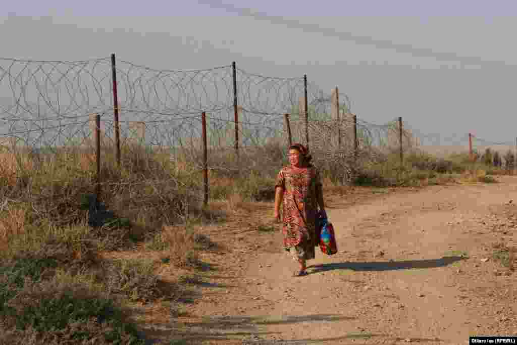 Женщина проходит вдоль линии границы в селе Достык.