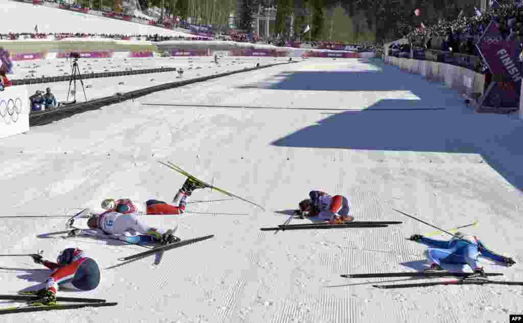 Athletes lie exhausted on the ground after the 7.5 kilometer + 7.5 kilometer skiathlon.