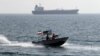 Iranian Revolutionary Guards drive a speedboat in front of an oil tanker during a ceremony to commemorate the 24th anniversary of the downing of Iran Air flight 655 by the US navy, at the port of Bandar Abbas on July 2, 2012. 