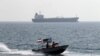 Iranian Revolutionary Guards drive a speedboat in front of an oil tanker during a ceremony to commemorate the 24th anniversary of the downing of Iran Air flight 655 by the US navy, at the port of Bandar Abbas on July 2, 2012. 