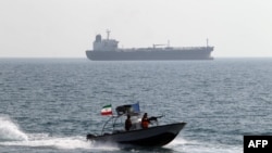 Iranian Revolutionary Guards drive a speedboat in front of an oil tanker during a ceremony to commemorate the 24th anniversary of the downing of Iran Air flight 655 by the US navy, at the port of Bandar Abbas on July 2, 2012. 