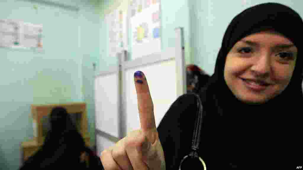 An Egyptian woman shows her ink-stained finger after she voted at a polling station in Giza district near Cairo on December 21. (AFP/Mohammed Abed)