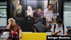 Реклама із закликом не поширювати фейкових повідомлень, вокзал у Куала-Лумпурі, Малайзія, 28 березня 2018 року