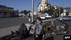 Жанчына праходзіць міма згарэлага аўтамабіля каля чыгуначнай станцыі ў Данецку 15 верасьня