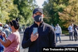 Мужчина в защитной маске с телефоном в руках на санкционированном властями митинге. Алматы, 13 сентября 2020 года.