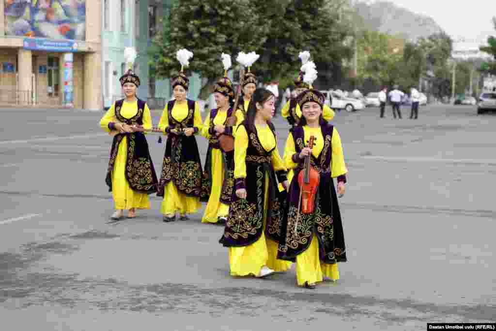 Musicians wearing traditional Kyrgyz dress prepare to play.
