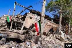 Iranian flags are placed by the rubble of a collapsed building following strikes at Sharif University of Technology in Tehran on April 7.