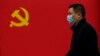 Чоловік у масці на тлі прапора Комуністичної партії Китаю, Ухань, 31 березня 2020 року