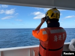 Un ofițer de pe nava de patrulare Yilan a Gărzii de Coastă din Taiwan urmărește o navă a Gărzii de Coastă chineze la nord-vest de mica insulă Pengjia. Imagine distribuită pe 29 decembrie 2025 de Garda de Coastă din Taiwan.