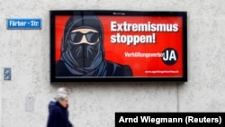 Бурка киіп жүруге қарсы науқан аясында ілінген постер. Постерде "Экстремизмді тоқтат" деп жазылған.