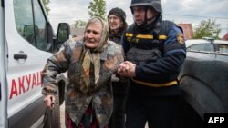This handout photograph taken and released by the Ukrainian Emergency Service on May 17 shows rescuers evacuating an elderly civilian from Russian shelling in the Kharkiv region.
