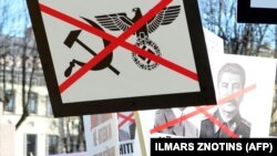 Плякаты з асуджэньнем нацызму і камунізму на акцыі ў Рызе, 2013, архіўнае фота.