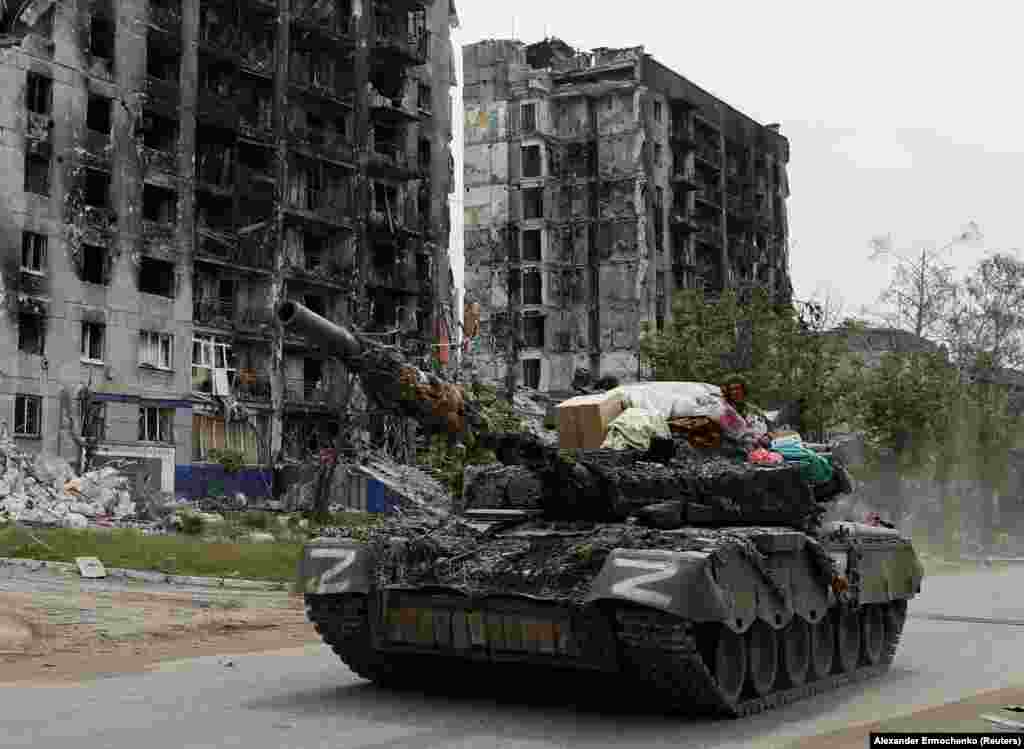 Egy orosz tank halad el megsemmisített lakóházak előtt a luhanszki régióban található Popasznában. Az orosz csapatok napok óta próbálják bekeríteni az ukránok állásait Popaszna és Szeverodonyeck között