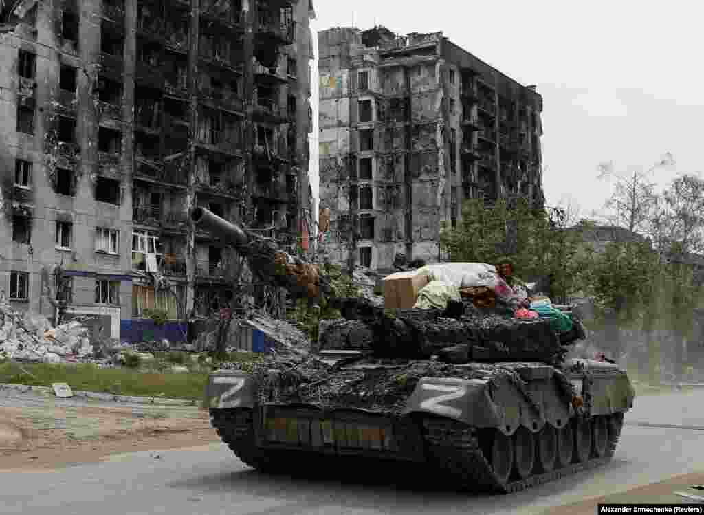 A Russian tank drives past destroyed residential buildings in Popasna, in the Luhansk region of eastern Ukraine. Russian forces are attempting to encircle Ukrainian positions between Popasna and Syevyerodonetsk, according to reports from the area.&nbsp;