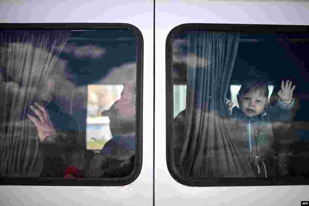 Un copil ucrainean refugiat face cu mâna dintr-un microbuz care-l duce pe el și pe mama lui mai departe în Moldova după ce au trecut granița moldo-ucraineană pe la Palanca, 12 apriie 2022 . O dramă umană avea loc atunci la granițele Ucrainei, cu mulți ucraineni care se refugiaseră după invadarea țării lor de către ruși încercând să revină la casele lor. (Photo by Christophe ARCHAMBAULT / AFP)