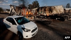 Аўтамабіль праязджае каля згарэлага грузавіка, які, як мяркуецца, падпалілі чальцы наркакартэлю ў адказ на ваенную апэрацыю супраць іх, 22 лютага 2026 году