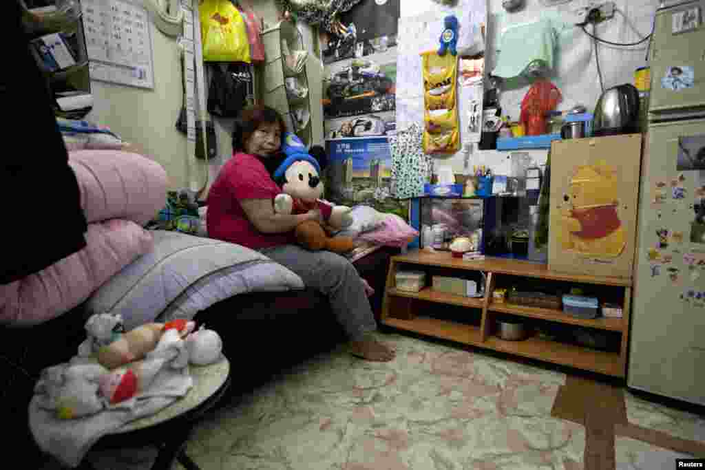 Lee Oi Lin, a 56-year-old woman, poses in her 4.1-square-meter subdivided flat inside an industrial building in Hong Kong. (2012 photo)