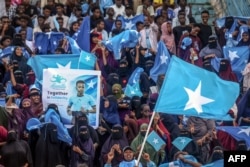 Susținătorii arbitrului internațional somalez Omar Abdulkadir Artan flutură steaguri și pancarte în timp ce îi urează bun venit acasă, cu ocazia întoarcerii sale nedorite în Somalia, la Mogadishu, pe 10 iunie 2026.