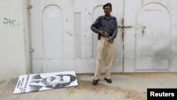 A policeman guards the sealed MQM party headquarters, where a poster depicting exiled party leader Altaf Hussain was torn down.