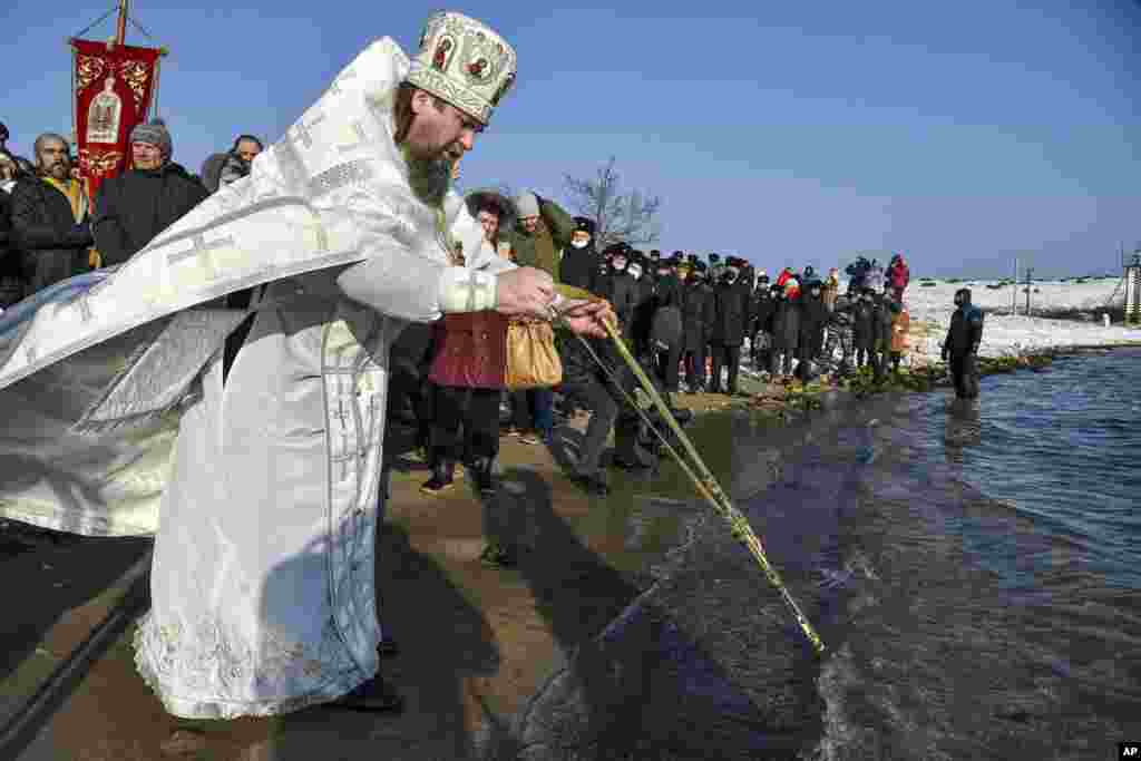 Православний священник освячує воду Чорного моря під час традиційного святкування Хрещення, коли температура впала приблизно до -6 градусів за Цельсієм у Севастополі, окупований Крим