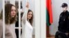 Belsat journalists Katsyaryna Andreyeva (right) shows the victory sign standing next to Daryya Chultsova before the start of their trial in Minsk on February 9.