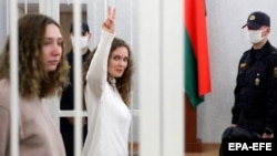 Belsat journalists Katsyaryna Andreyeva (right) shows the victory sign standing next to Daryya Chultsova before the start of their trial in Minsk on February 9.