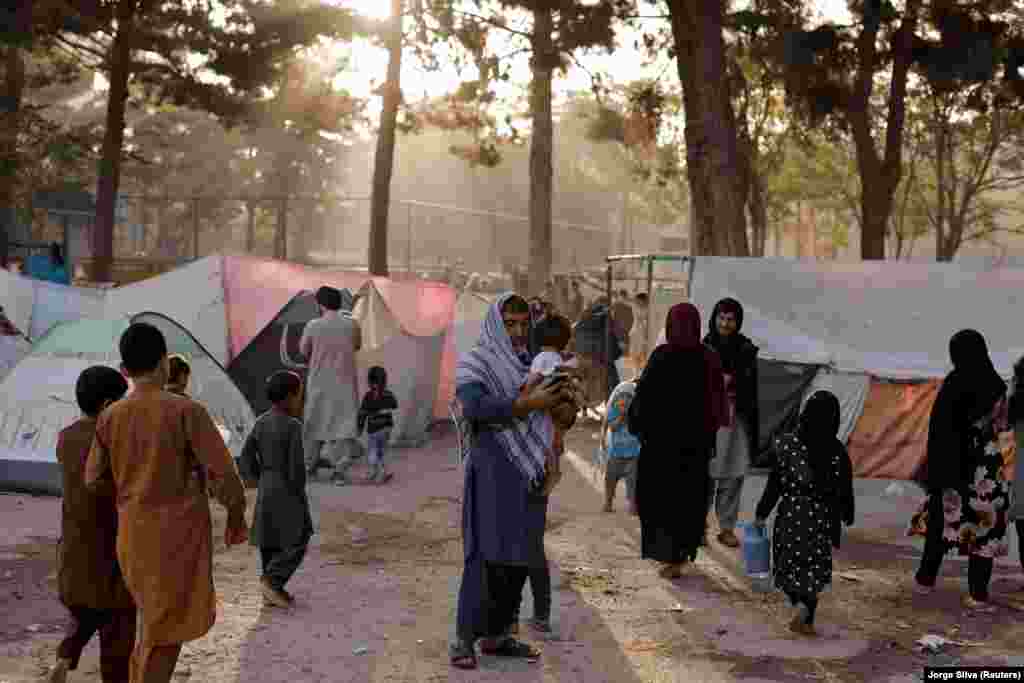 Displaced Afghan families who have fled the violence in their provinces stand near tents at a makeshift shelter in the Shahr-e Naw park in Kabul on October 4.&nbsp;