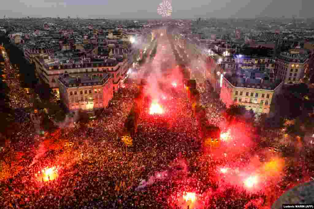 Людзі ў Парыжы сьвяткуюць перамогу францускай зборнай у Чэмпіянаце сьвету па футболе.