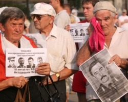 Protesters hold pictures of victims and a poster reading "Demand international investigation of missing cases!" at a rally in the center of Minsk on August 17.