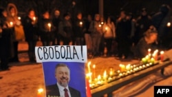 Belarusian opposition supporters light candles near a picture of jailed opposition presidential candidate Andrey Sannikau at a prison's wall during a demonstration in Minsk on December 21.