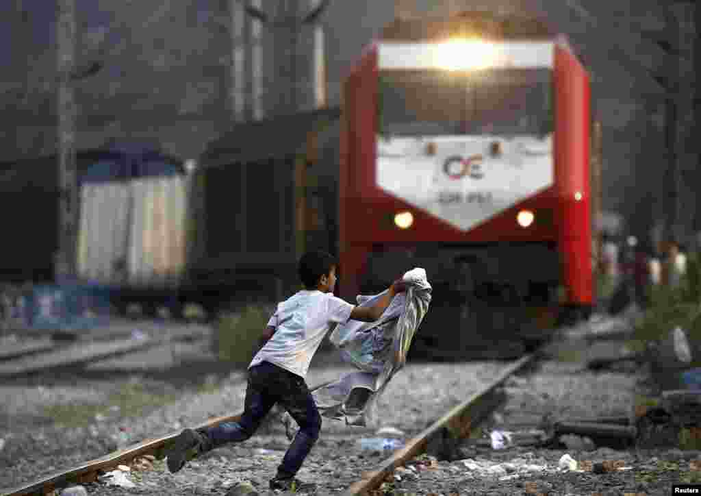 A Syrian refugee boy runs across rail tracks as a freight train approaches near Greece's border with Macedonia, outside the Greek village of Idomeni. (Reuters/Yannis Behrakis) 