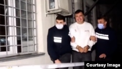 A smiling Mikheil Saakashvili is shown in handcuffs in a video released by the Georgian Interior Ministry.