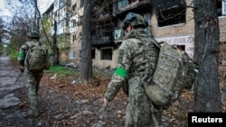 Ukrajinski vojnici pored stambene zgrade oštećene u ruskim napadima u gradu Kostjantinovki, na prvoj liniji fronta u Donjeckoj oblasti 1. novembra 2025.