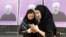 Iranian women stand in front of election posters for President Hassan Rohani in city of Karaj.