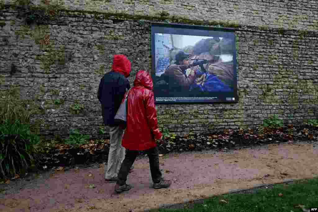 People pass by a photograph by AFP photographer Ahmed Deeb displayed on a street in Bayeux, France,  as part of the 22th edition of the Bayeux-Calvados award for war correspondents. (AFP/Charly Triballeau)