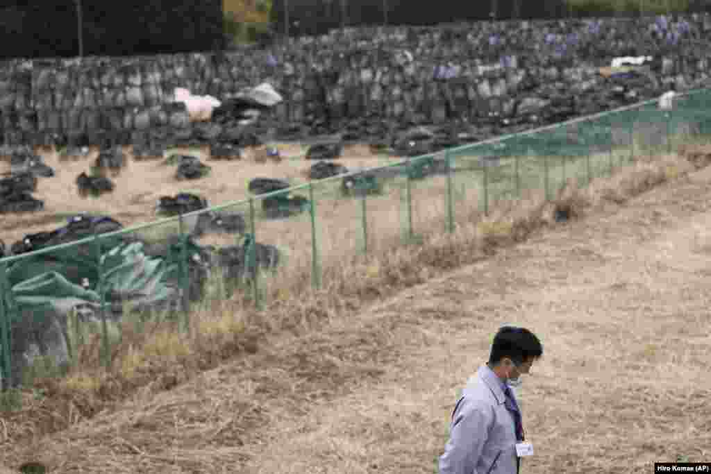 Yuya Hatakeyama, un oficial al orașului Tomioka, trece pe lângă un loc de depozitare temporară pentru saci de resturi și deșeuri radioactive. El conduce reporterii AP printr-o zonă care încă nu a fost redată locuitorilor din orașul Tomioka, prefectura Fukushima, nord-estul Japoniei, vineri, 26 februarie 2021. Hatakeyama a fost&nbsp; forțat să părăsească regiunea pe când era elev de liceu de 14 ani. El s-a întors în oraș ca funcționar debutant. Acum, la vârsta de 24 de ani, Hatakeyama vrea să ajute la refacerea comunității și la revenirea locuitorilor din mult-încercatul oraș.