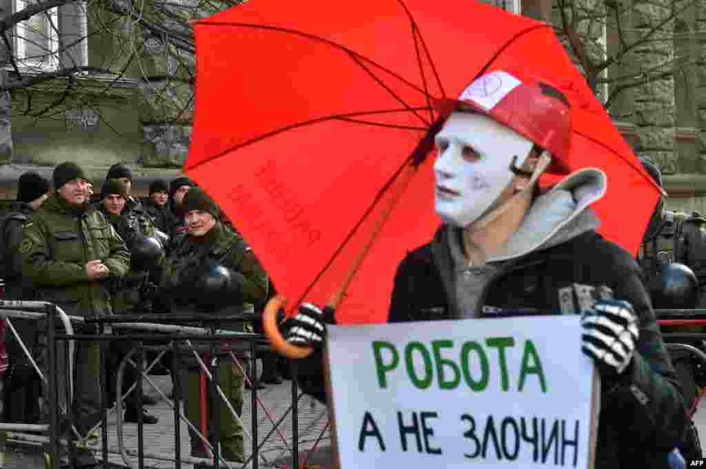 Policemen smile as a man wearing a mask holds a placard reading &quot;Worker but not criminal&quot; during a march of sex workers in Kyiv. (AFP/Serhiy Supinsky)