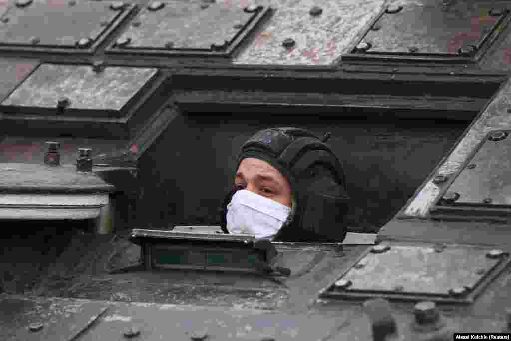 A Russian serviceman wearing a protective mask looks out of a military vehicle during a rehearsal for the annual Victory Day celebrations. The event in Yekaterinburg is expected to feature 13 planes and nine helicopters.