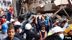 Rescue workers carry a body out of the wreckage of the collapsed 10-story Metropolis building in the port city of Abadan.