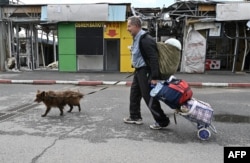 A resident walks his dog past the damaged market in Saltivka on May 29.