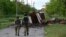 Ukrainian soldiers walk along a path partially blocked by vehicle destroyed in fighting with Russian forces. 