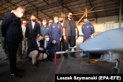 Președintele Poloniei, Andrzej Duda (aplecat, cu o mască neagră) inspectează o dronă de luptă Bayraktar TB2 în Turcia, mai 2021.